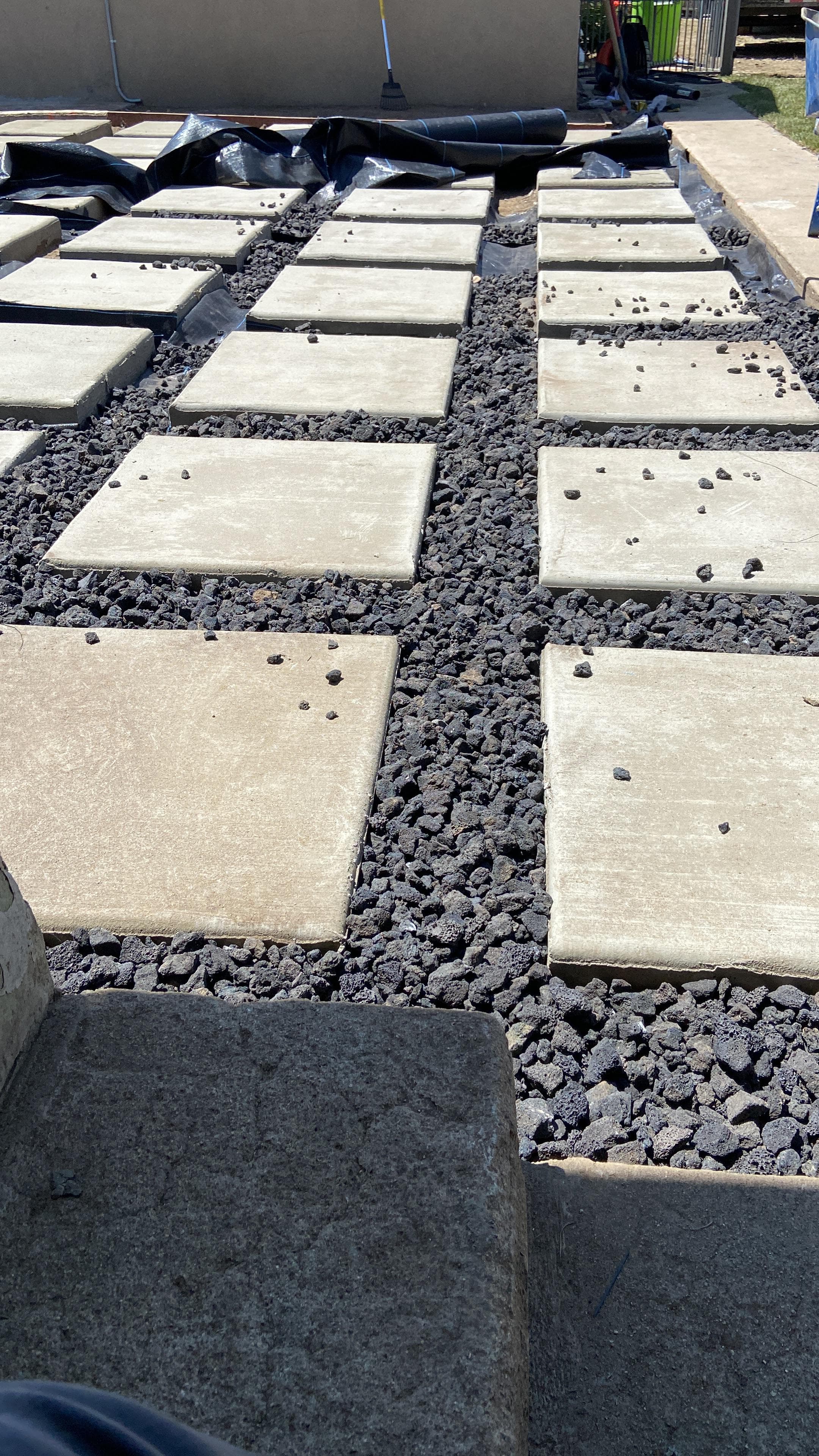 Square concrete pavers arranged in a grid with dark lava rock filling the gaps.